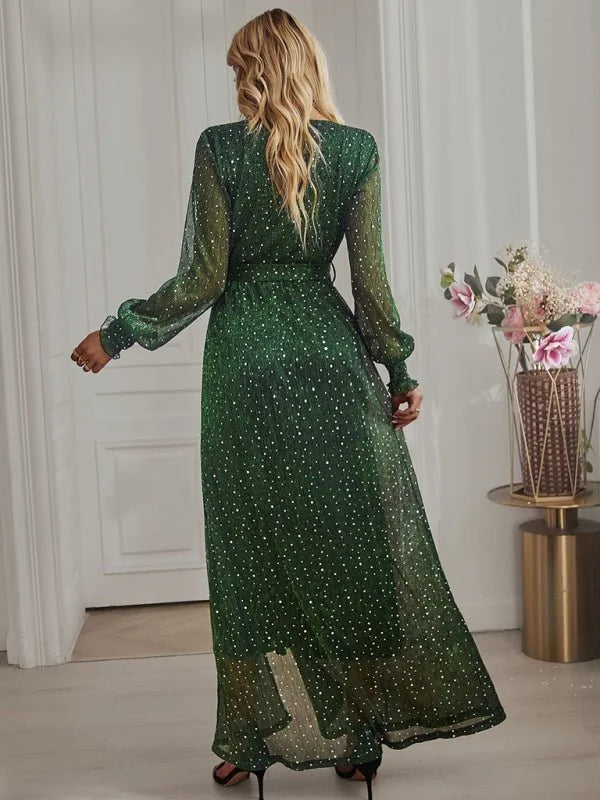 Emerald green shimmery maxi dress with white polka dots, long sleeves, and a flowing skirt.