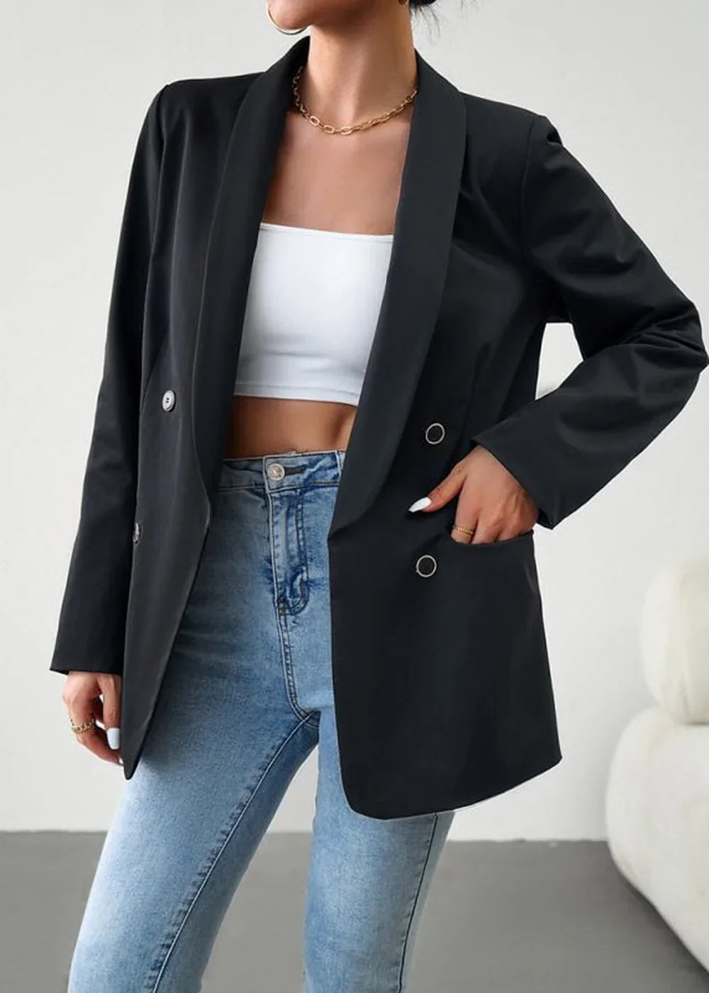 Black double-breasted blazer with silver buttons and blue denim jeans on model.