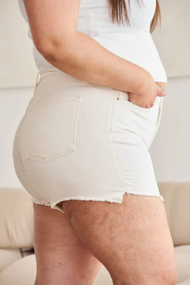 Cream denim shorts with frayed hem and visible stitching on the thighs.