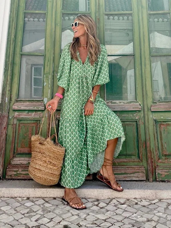 Green and white geometric print maxi dress with puff sleeves and straw bag.