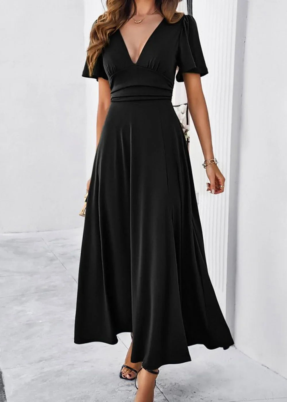 Woman in a flowing black V-neck maxi dress with short flutter sleeves.