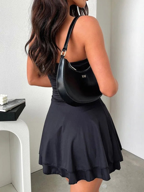 Black viscose fiber mini dress with flared skirt and black shoulder bag.