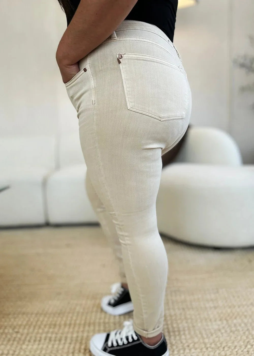 Close-up of light bone colored denim jeans on a model, showing pocket and leg details.