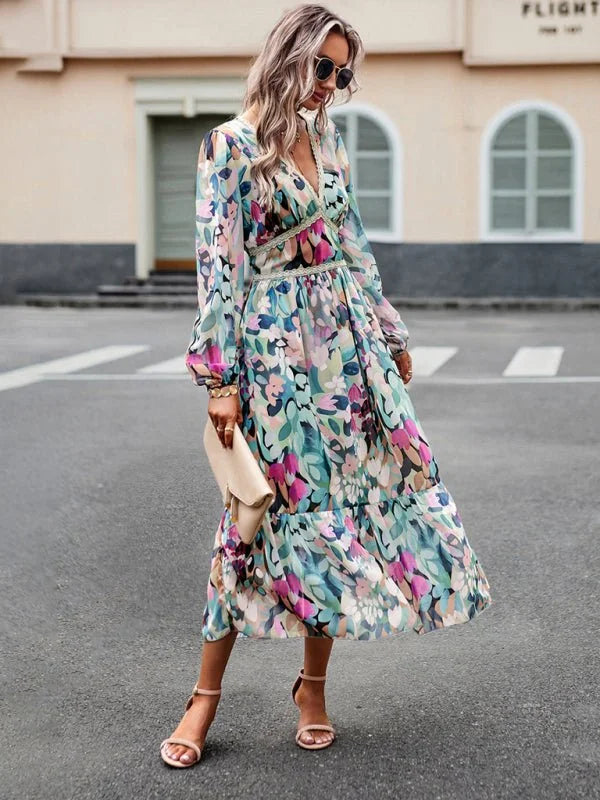 Flowy maxi dress with a colorful abstract floral print, V-neck, long sleeves, and nude heeled sandals.