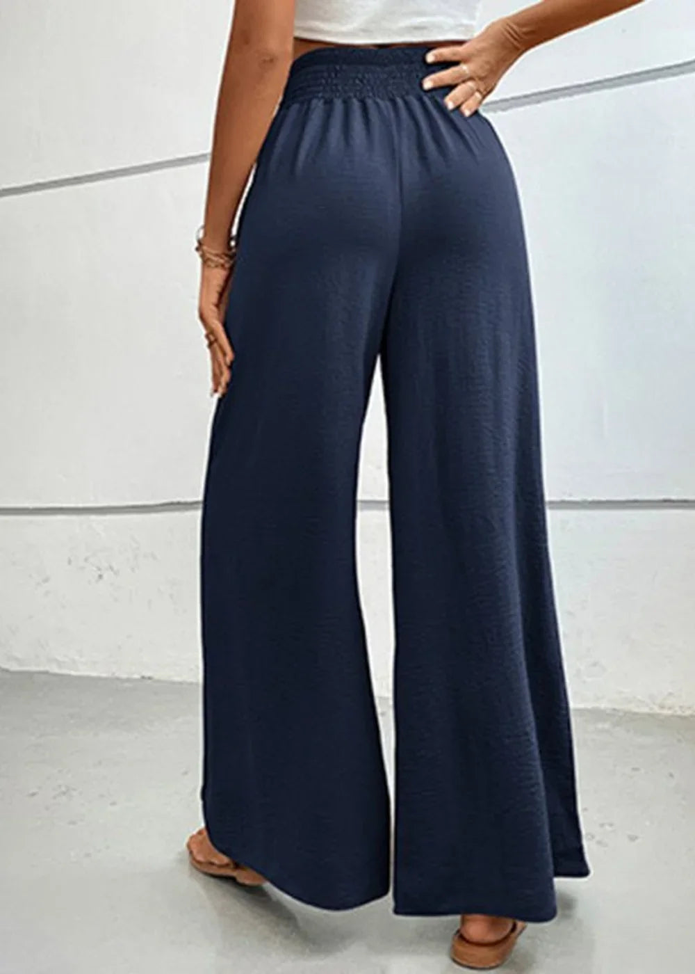 Navy blue wide-leg pants with smocked waistband and textured fabric, shown from the back.