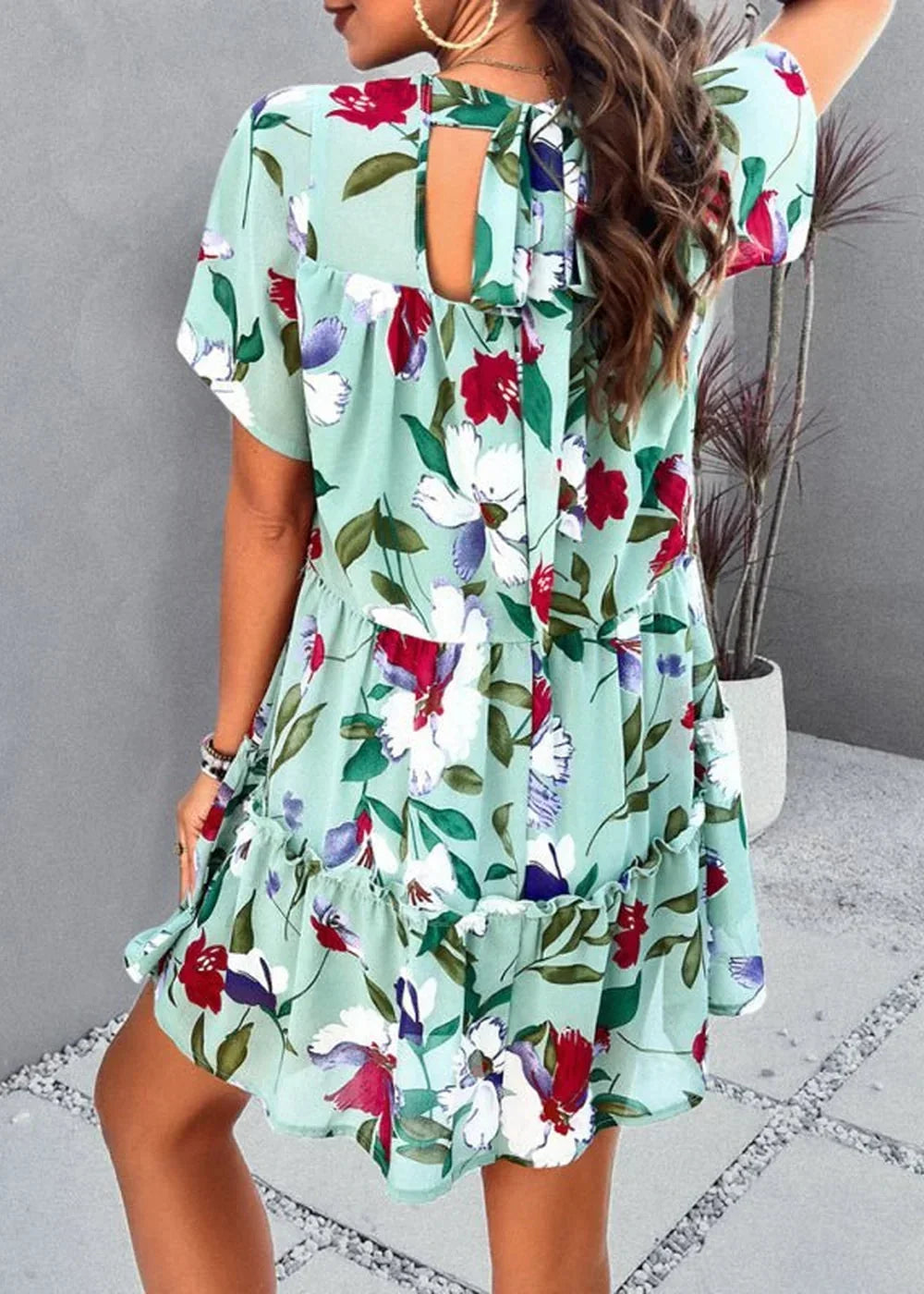 Light green floral print dress with ruffle trim and tie-back detail on model.