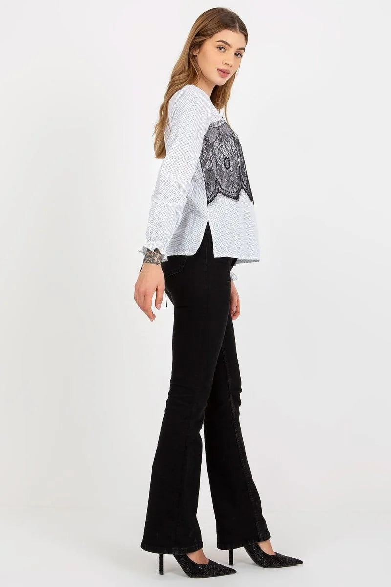 Woman in white polka dot blouse with black lace and black flared jeans.