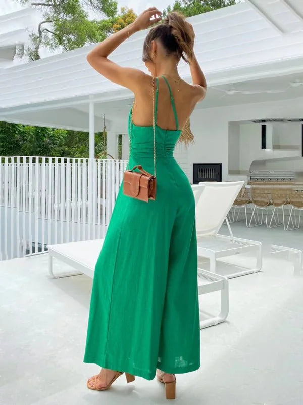 Woman in a vibrant green wide-leg jumpsuit with a brown crossbody bag, seen from the back.