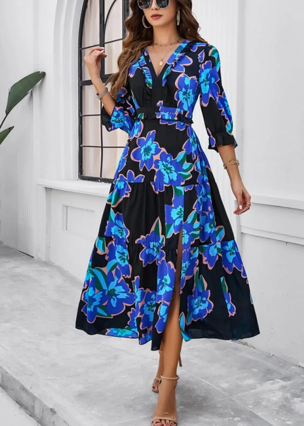 Black midi dress with a vibrant blue floral print, V-neck, ruffled details, and a thigh-high slit.