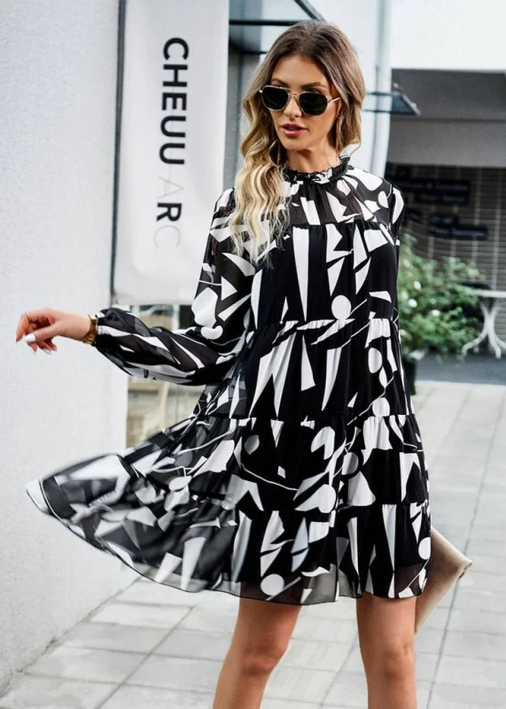 Black and white abstract print tiered chiffon dress with long sleeves and sunglasses on model.