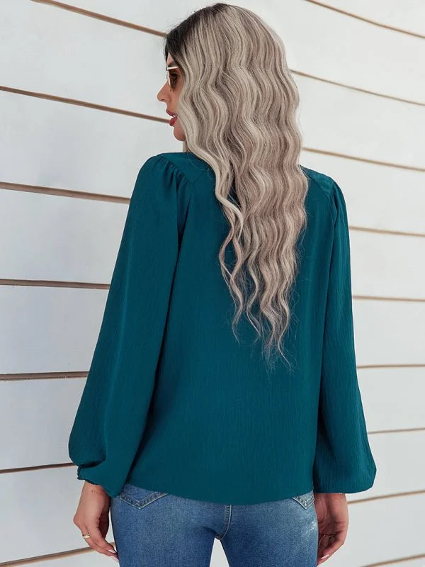 Teal textured long-sleeve blouse with bishop sleeves on a model.