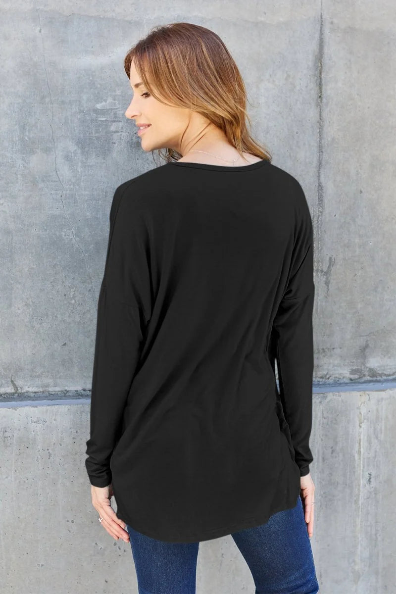 Black long-sleeve relaxed fit top with a rounded hem, shown from the back on a model.