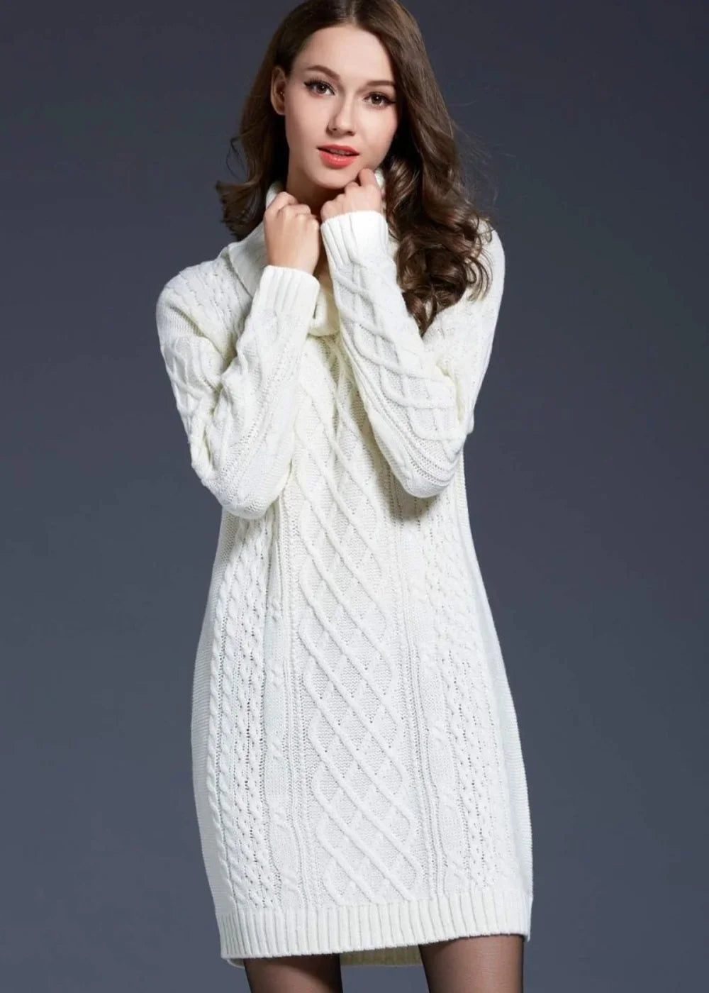 Woman in a white cable-knit sweater dress with a cowl neck, arms crossed.