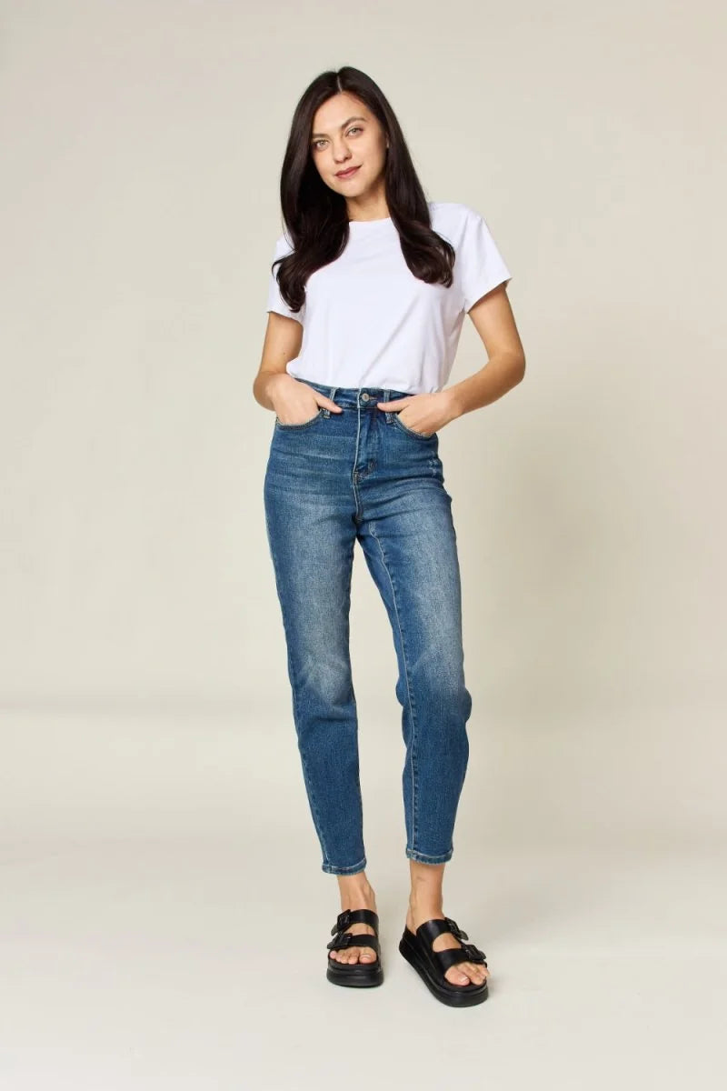 Full-length shot of a woman wearing distressed blue denim jeans and black slide sandals.