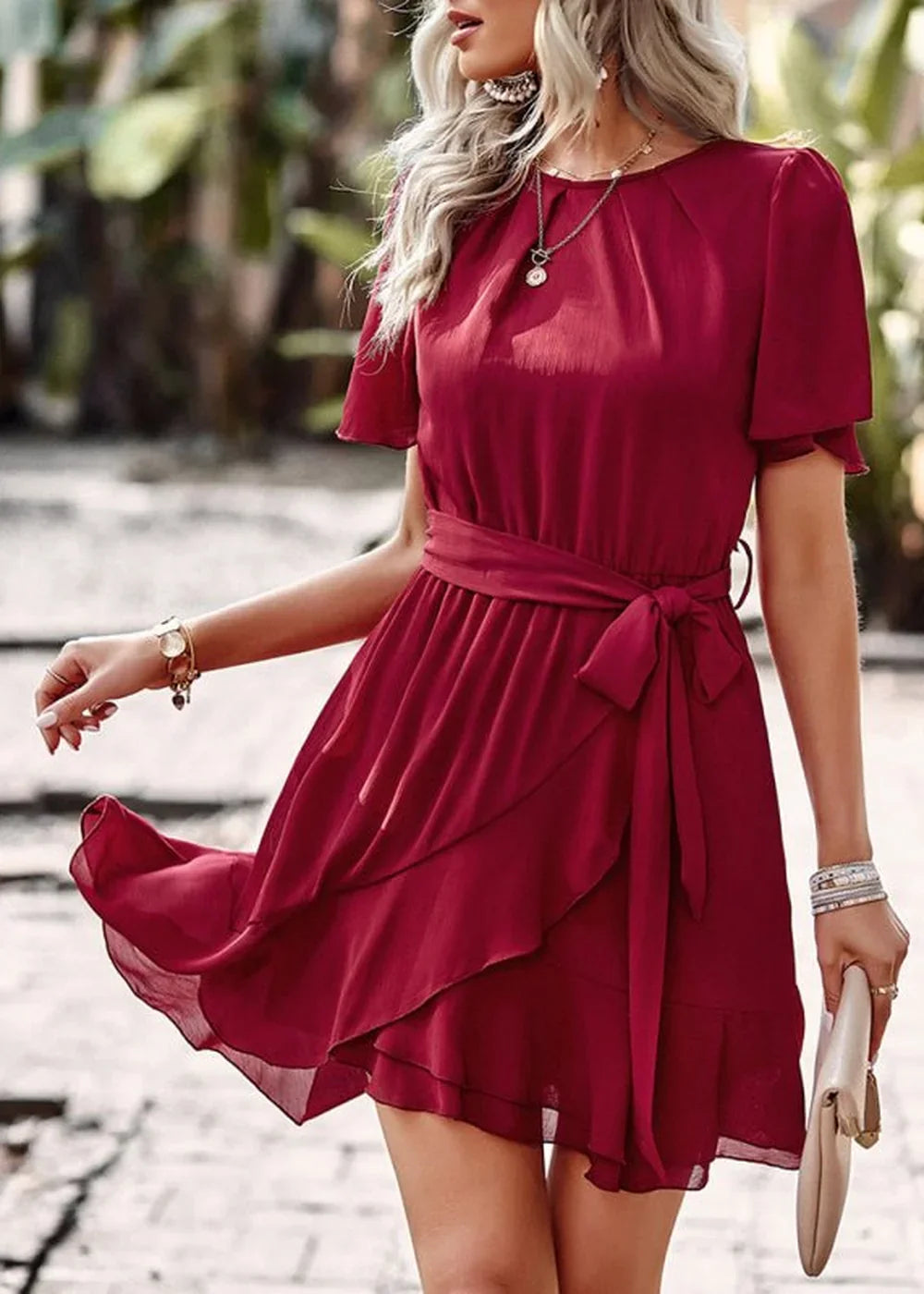 Flowy burgundy wrap dress with flutter sleeves and a tie waist, shown on a model.