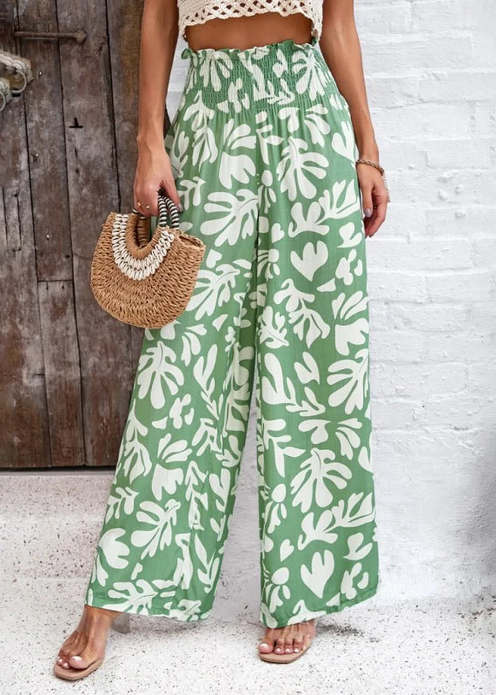 Green wide-leg pants with a white abstract leaf print, high smocked waist, and side slit detail.
