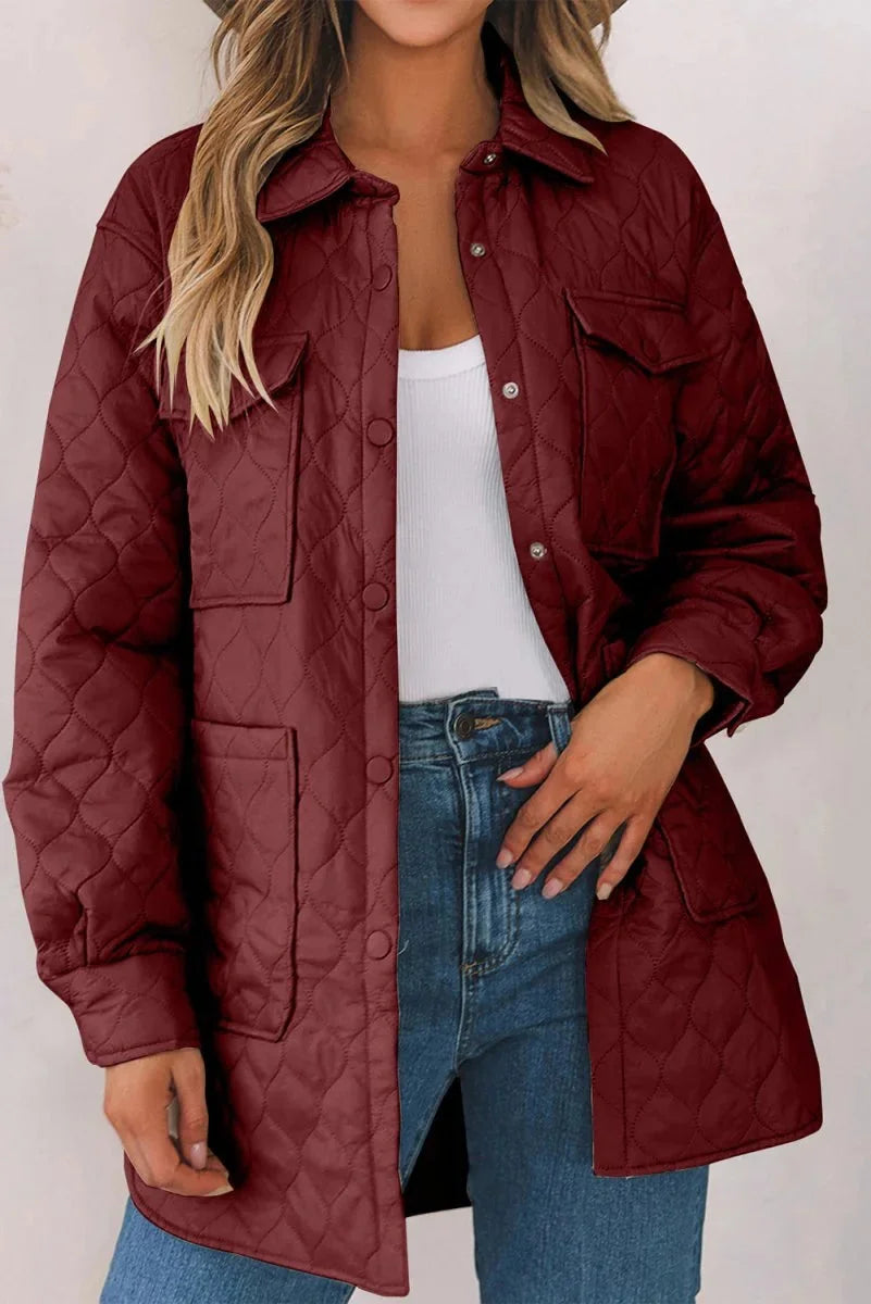 Quilted burgundy jacket with snap closures, pockets, and collar, worn over a white top and jeans.