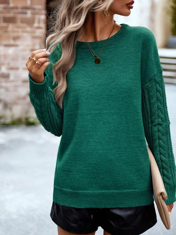 Emerald green acrylic sweater with cable knit sleeves and gold pendant necklace on model.