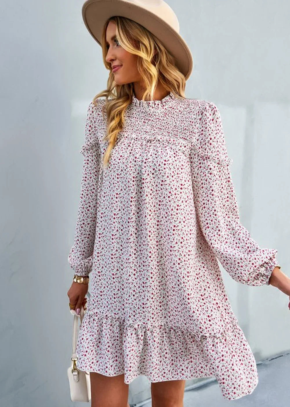 Woman wearing a white floral print dress with smocked bodice and ruffled hem, accessorized with a wide-brim hat and small ...