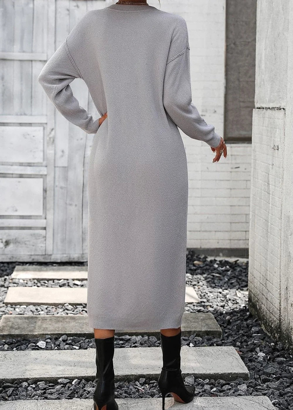 Back view of a gray, ribbed knit midi sweater dress with long sleeves, worn with black heeled boots.