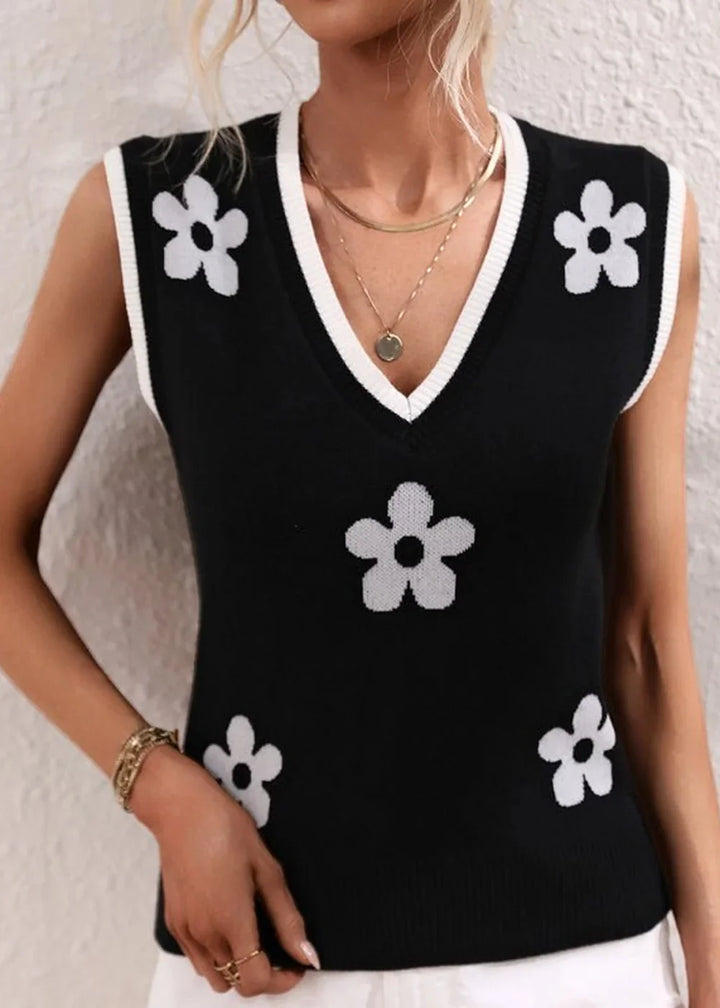 Black knit vest with white floral pattern and white trim, v-neck, on model.