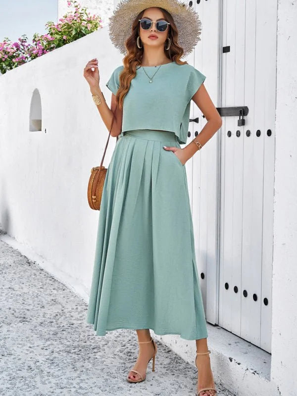 Light green viscose two-piece set with pleated skirt and cap sleeves on a model.