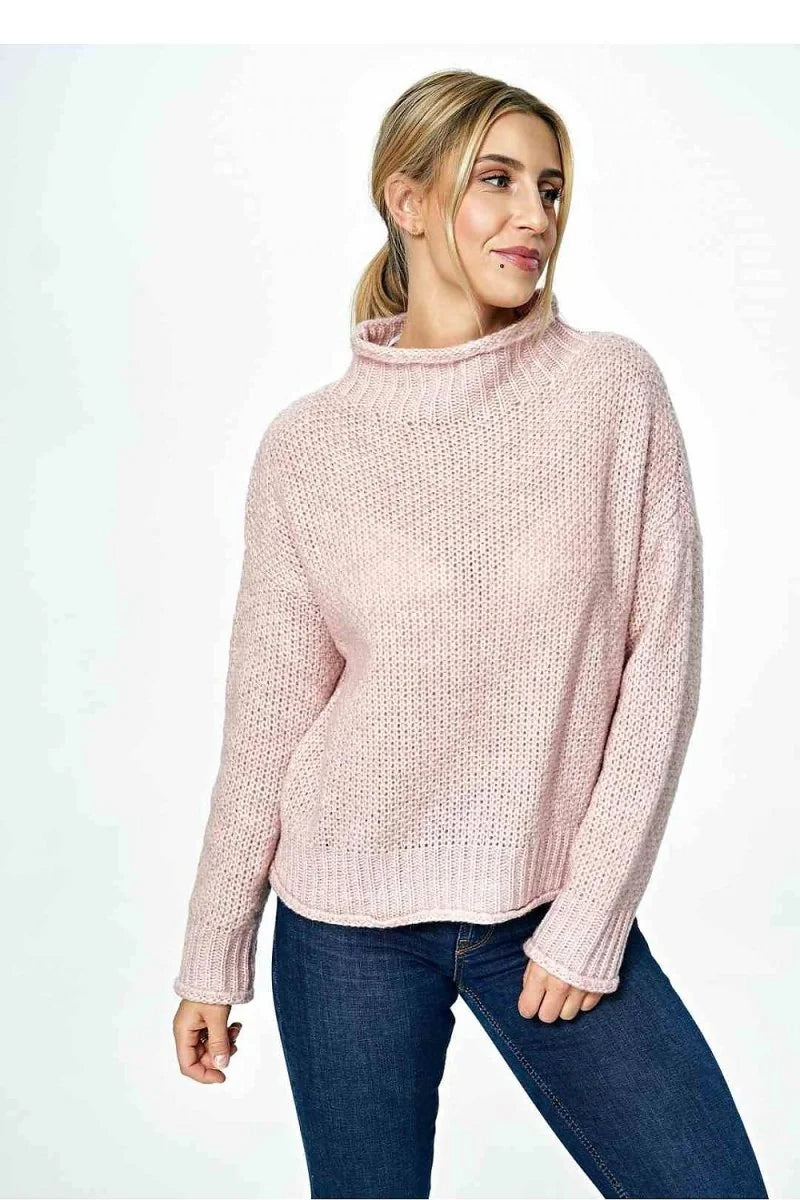 Light pink textured knit sweater with a high neckline and cuffed sleeves on a model.