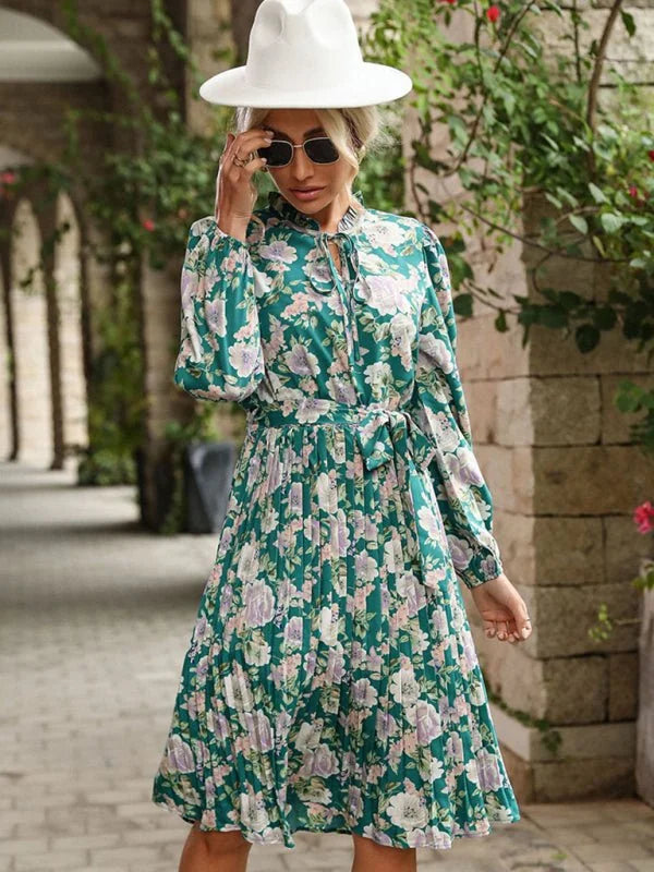 Green floral print dress with a tie neck and pleated skirt.