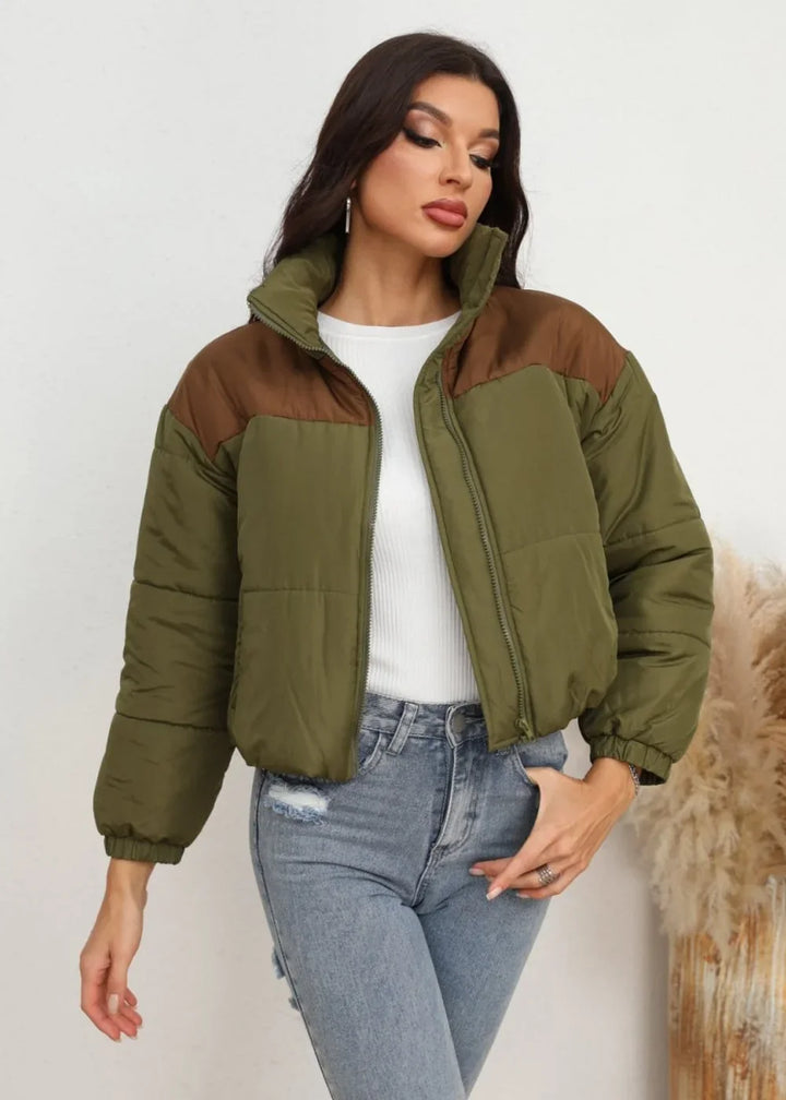 Olive green puffer jacket with brown color block detail, on a model wearing distressed denim.