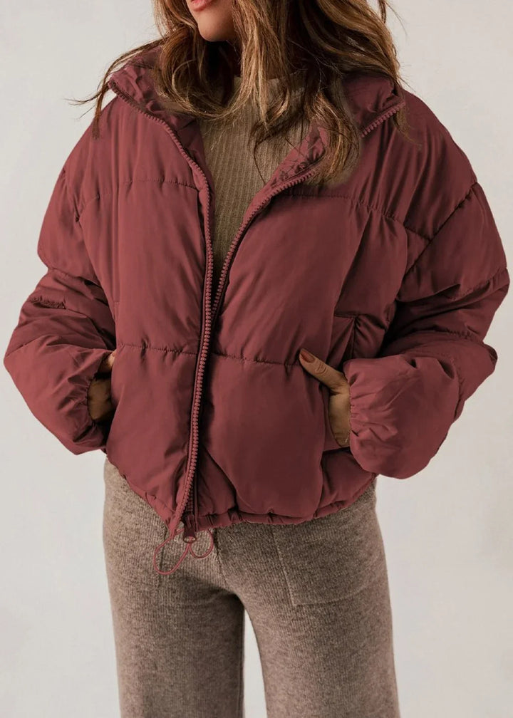 Maroon puffer jacket with quilted texture, zipper closure, and brown knit pants.