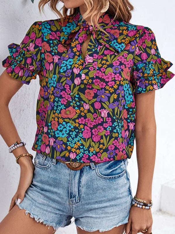 Floral print blouse with a bow neckline and ruffled short sleeves, paired with distressed denim shorts.