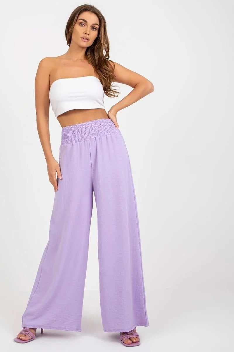 Lavender wide-leg pants with a smocked waistband and a textured fabric, worn by a model with a white bandeau top.