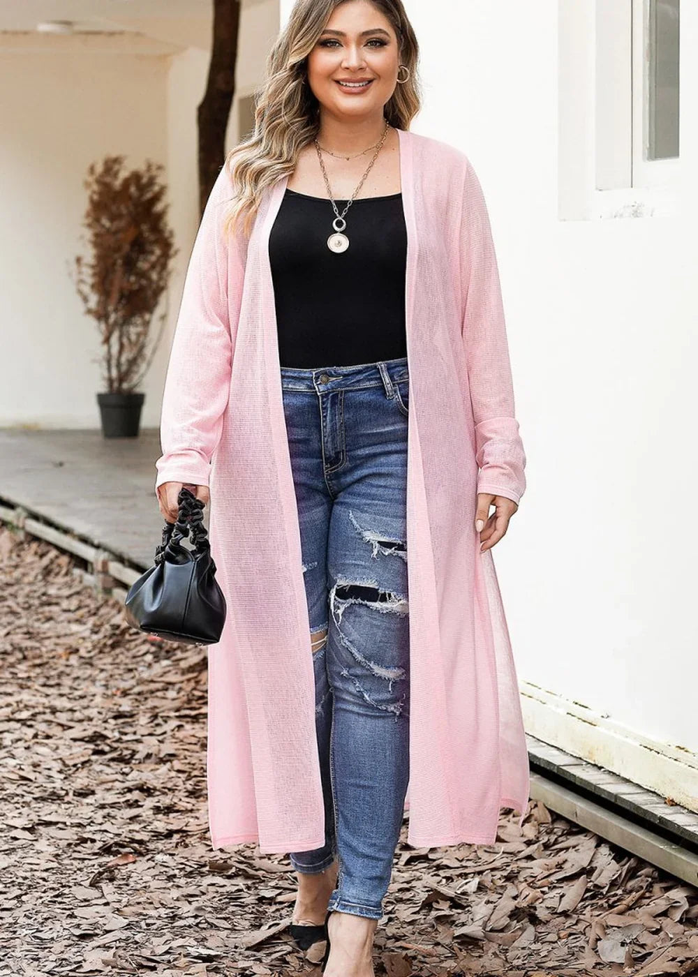 Pink sheer duster cardigan with distressed denim jeans on a model.