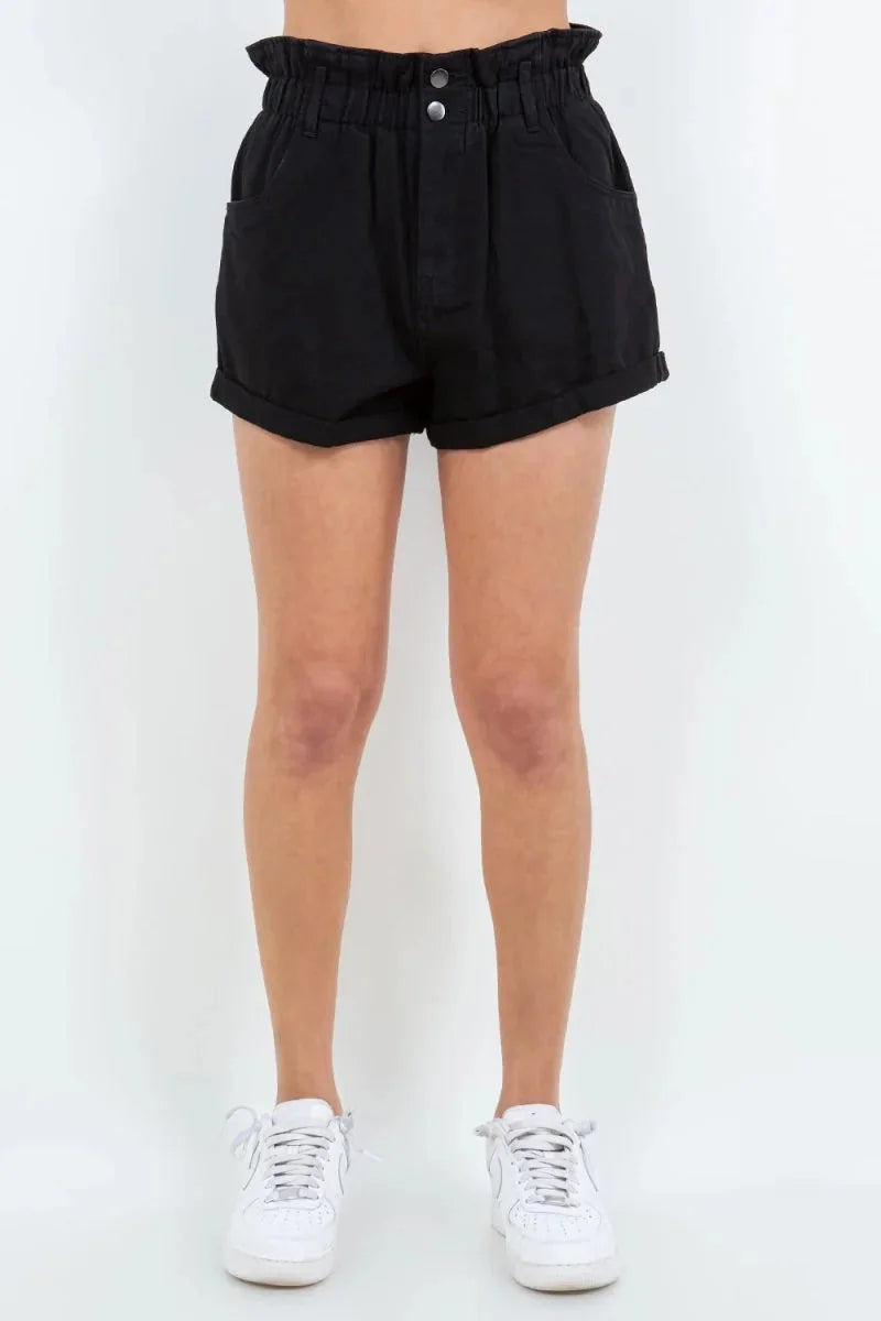 Black denim shorts with a ruffled high waist, two front buttons, and cuffed hems, shown on a model.