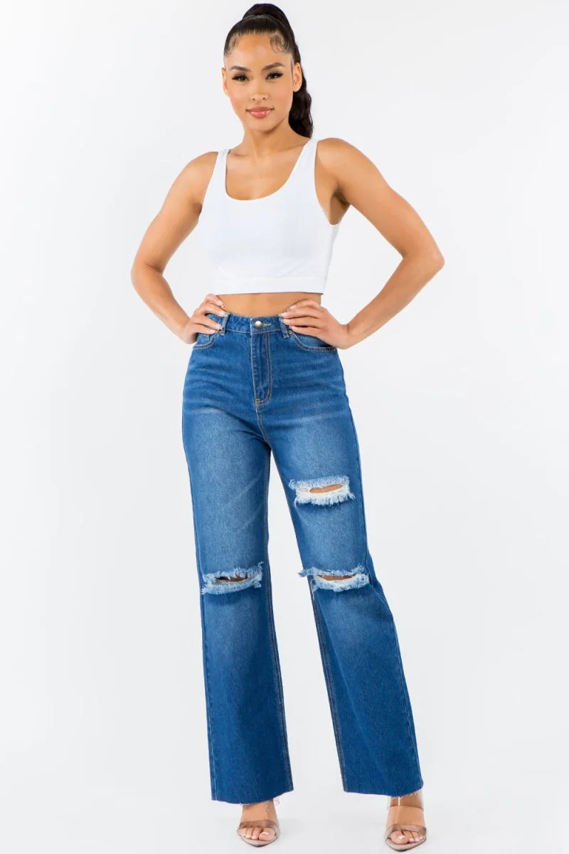Distressed blue denim jeans with a wide-leg fit and frayed hem, on a model.