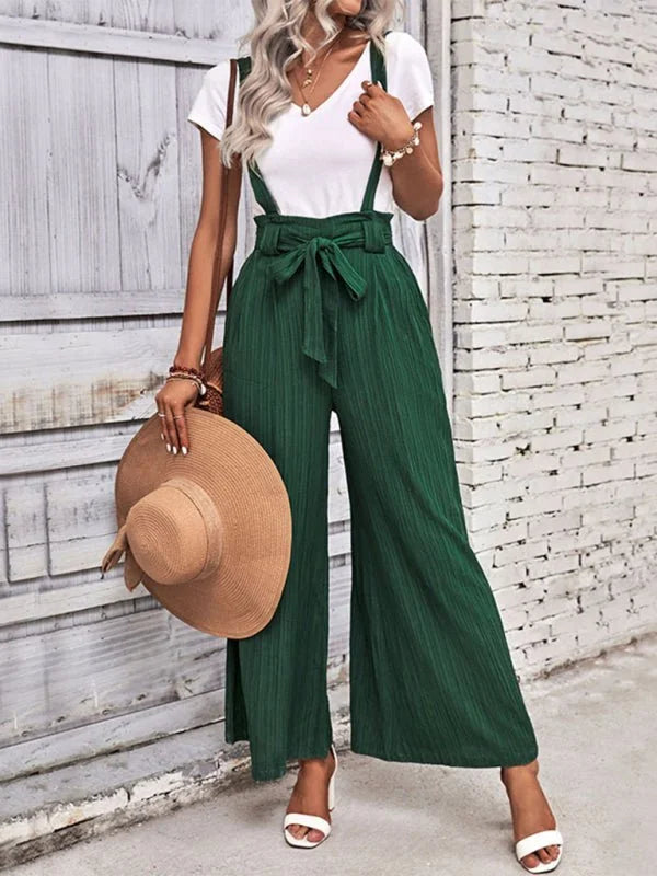 Emerald green wide-leg jumpsuit with a tie waist and pleated texture, worn by a model with white sandals.