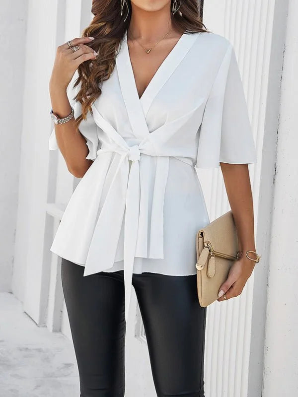 White wrap-style blouse with tie waist, flutter sleeves, and a deep V-neck.