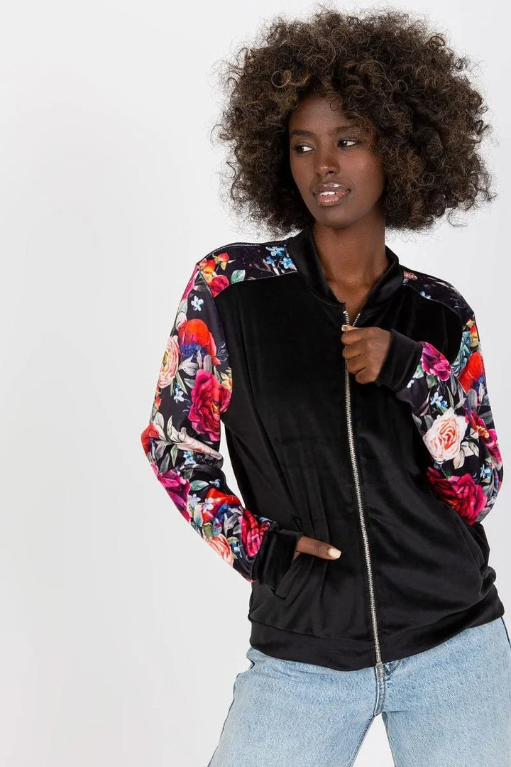 Black velvet bomber jacket with vibrant floral print sleeves on a model.