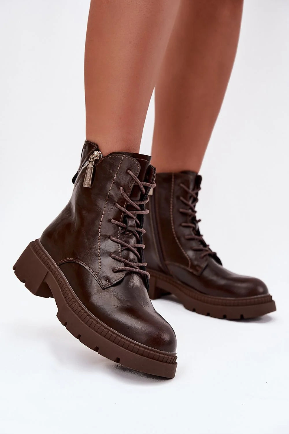 Brown leather lace-up combat boots with a side zipper and thick lug sole on model.