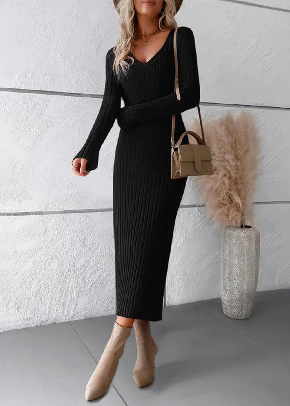 Black ribbed V-neck midi sweater dress with long sleeves and beige ankle boots, worn with a small tan crossbody bag.