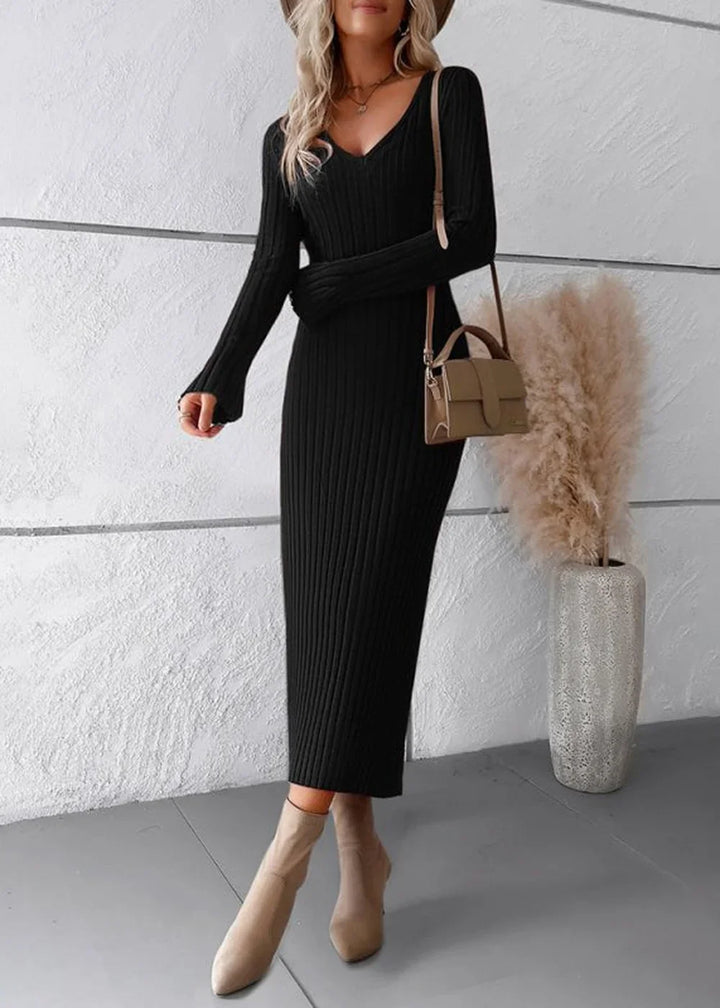 Black ribbed V-neck midi sweater dress with long sleeves and beige ankle boots, worn with a small tan crossbody bag.
