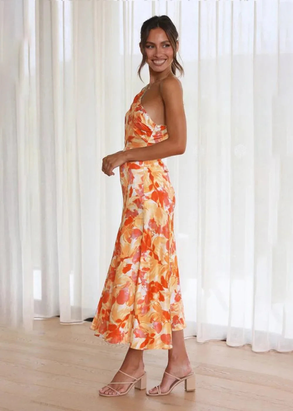 Orange and yellow floral print maxi dress with a one-shoulder neckline, shown on a model.