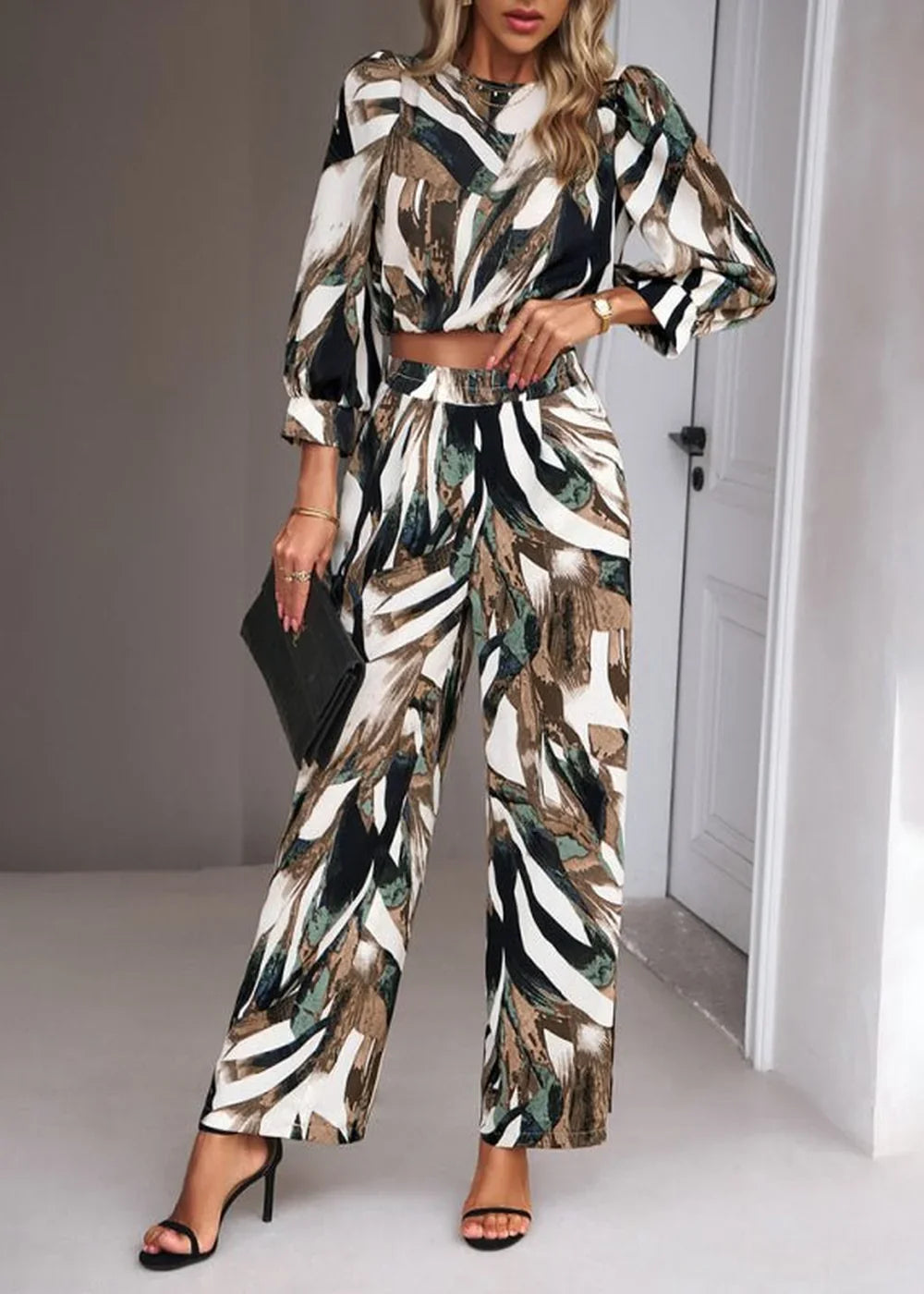 Woman in abstract print wide-leg pantsuit with puff sleeves and high heels.