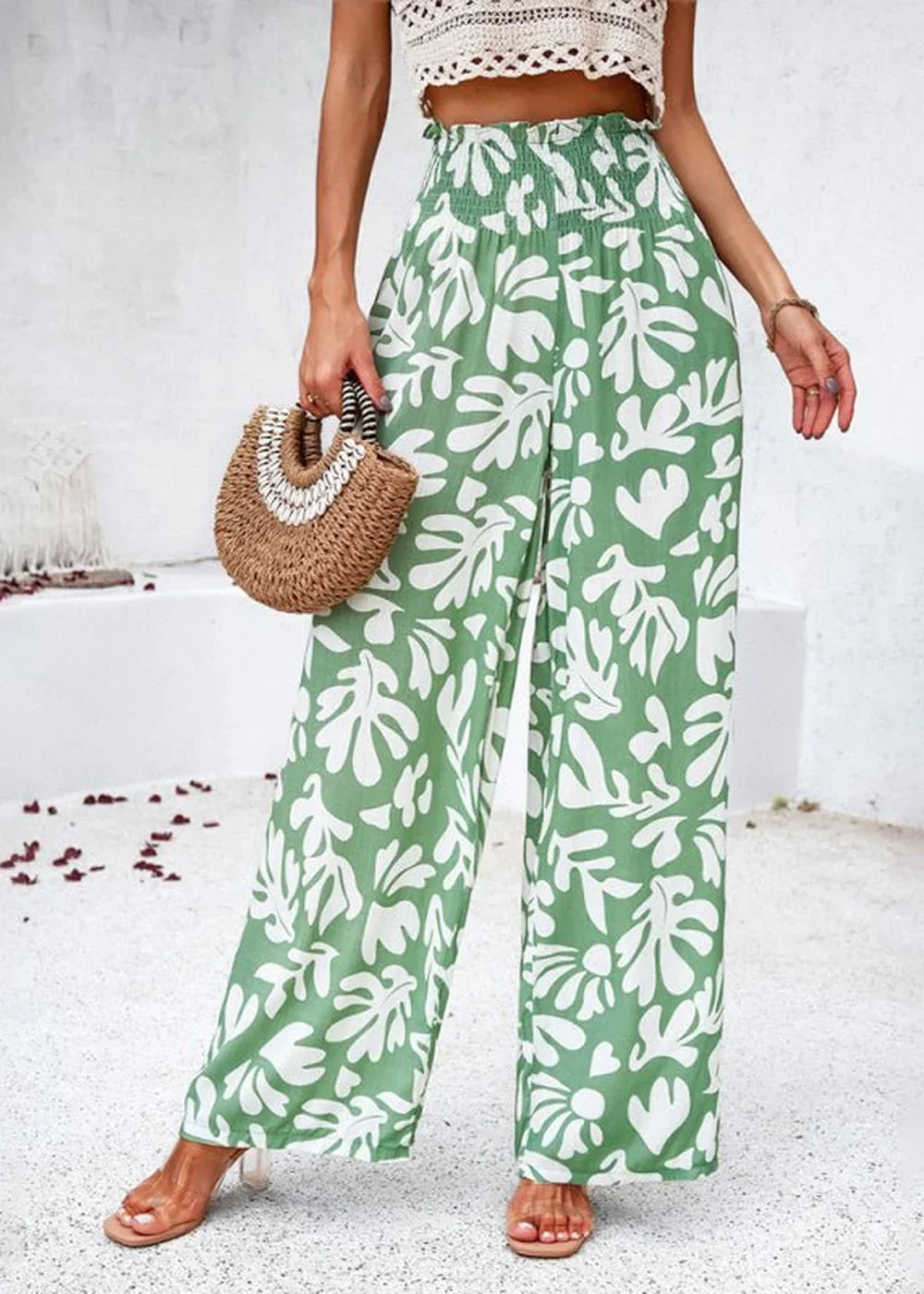 Green wide-leg pants with a white abstract floral print and smocked waistband, worn with tan sandals.