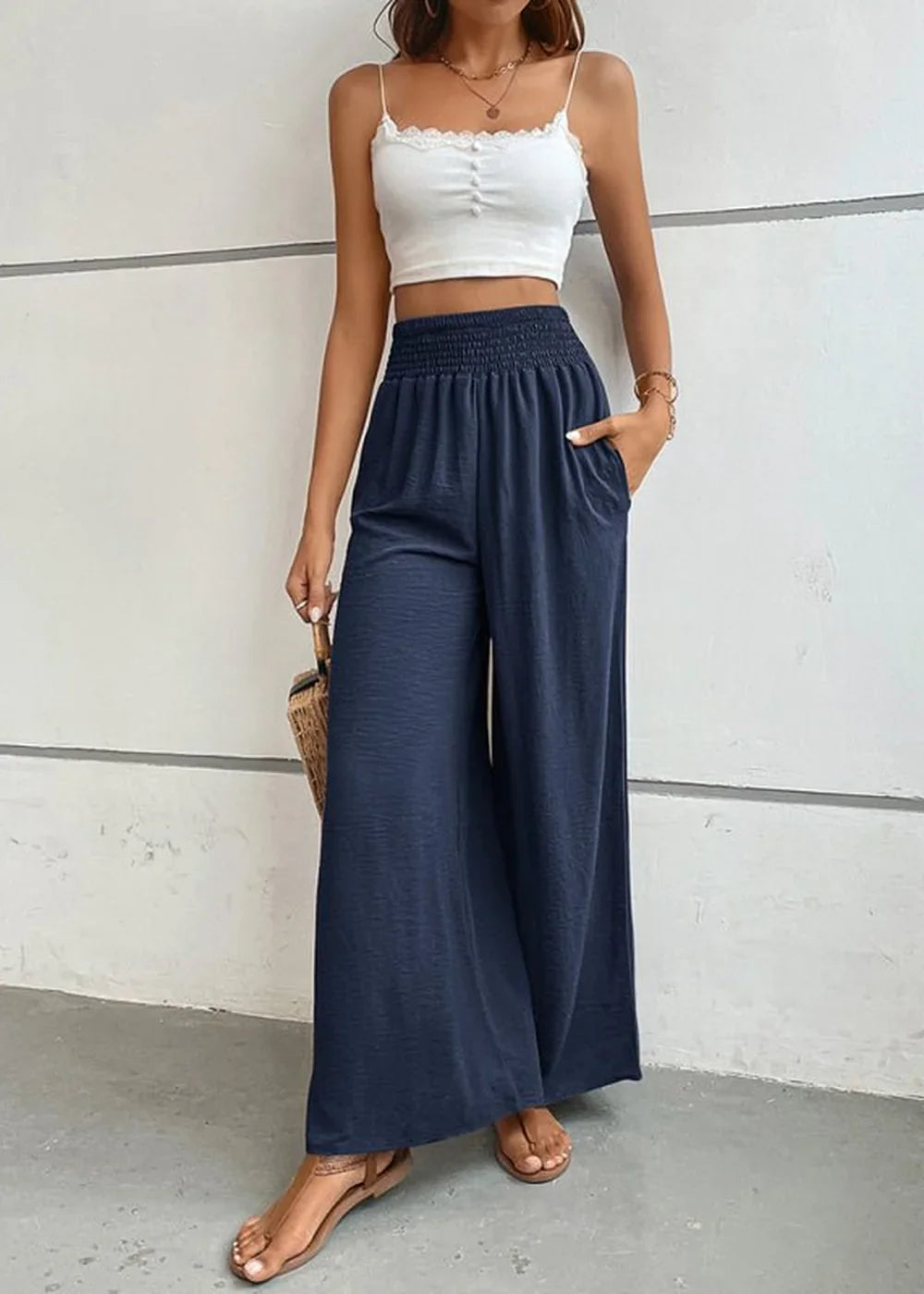 Navy blue wide-leg pants with smocked waist and pockets, shown on a model with a white cropped top.