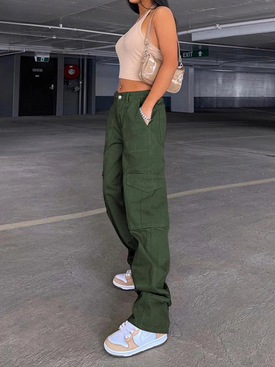 Full-length shot of dark green cargo pants on a model, with a beige tank top and white and peach sneakers.