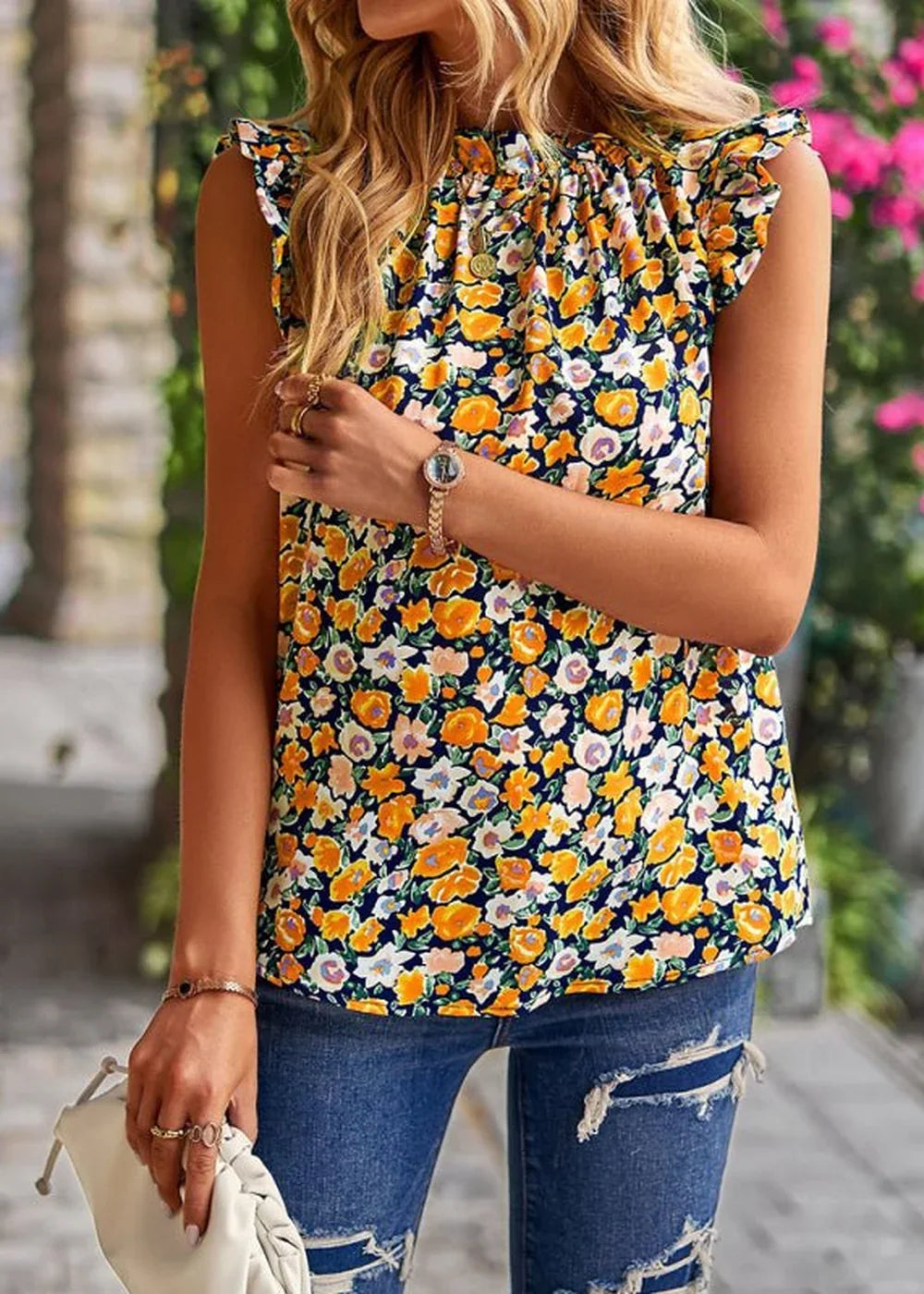 Navy blue top with an all-over yellow, orange, and white floral print, featuring ruffled cap sleeves and a high neckline.