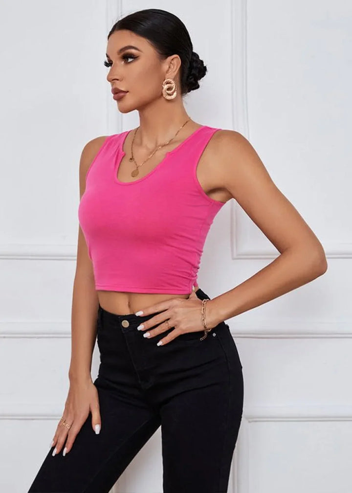 Hot pink ribbed crop top with a notched neckline and ruched sides, worn with black jeans.