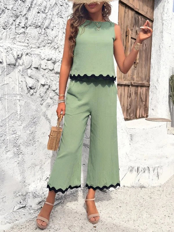 Light green viscose wide-leg pants with black scalloped trim on the hem.