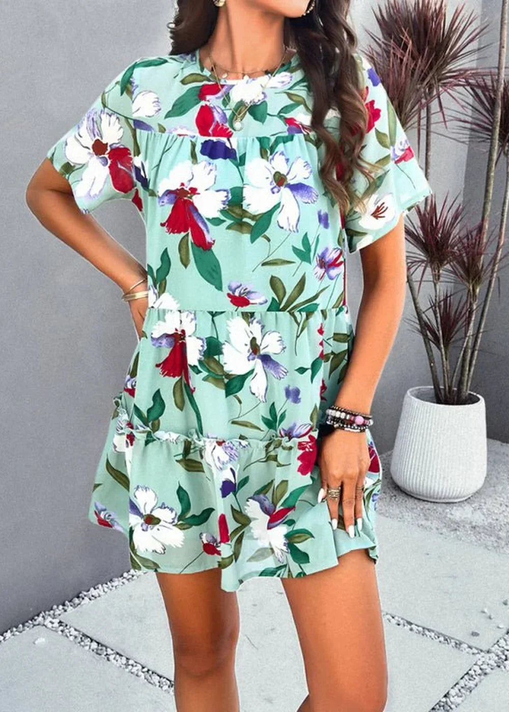 Light mint green tiered mini dress with a vibrant floral print of red, white, and purple flowers.